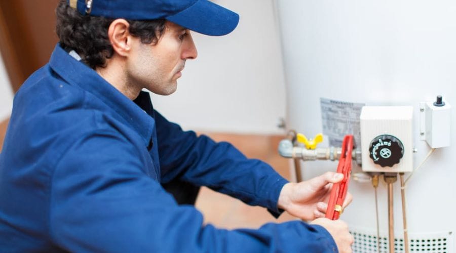 Plumber adjusting the controls of a gas water heater