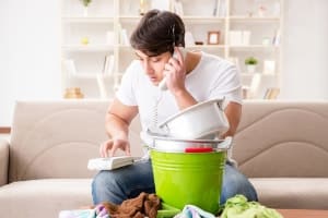 man calling about a plumbing emergency, buckets catching tripping water in living room